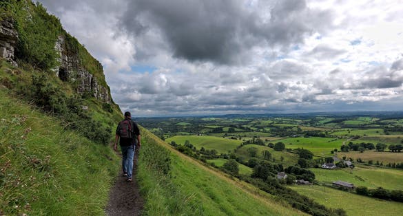 photo of Man walking towards the Caves of Kersh, overlooking the green rural landscape of County Sligo, Ireland