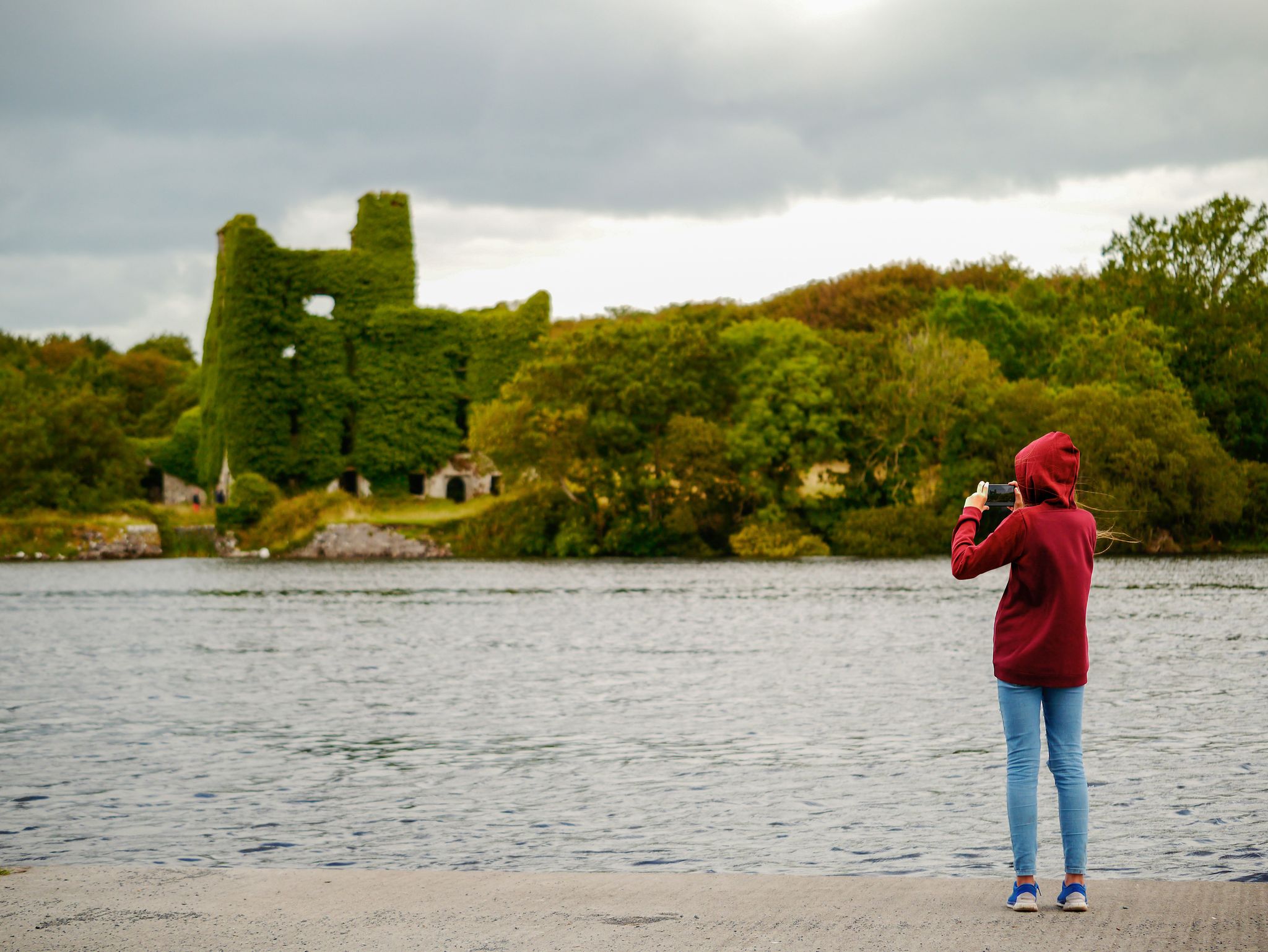 photo of Girl teenager taking picture on her smart phone of Menlo castle, Ireland, Galway, Concept: tourist, adventure, technology,