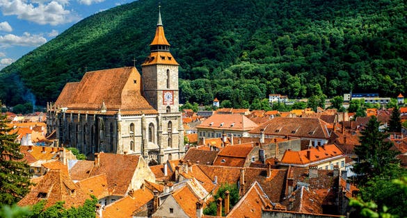 Photo of Brasov cityscape with black cathedral and mountain on backround in Romania .