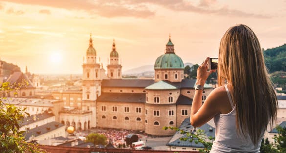 Photo of tourist taking a photo with mobile of beautiful sunset in Salzburg, Austria.