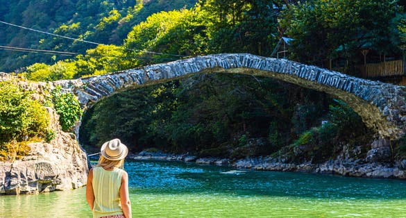 Photo of girl traveler enjoys scenic view of Makhuntseti bridge in Keda District of Ajara in village of Makhuntseti, Georgia. 