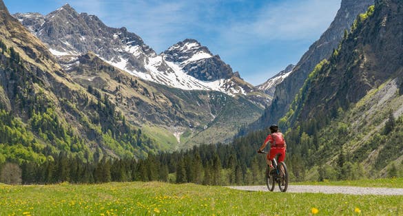 Photo of pretty senior woman riding her electric mountain bike the Oy Tal Valley near Oberstdorf, Allgau Alps, Bavaria, Germany