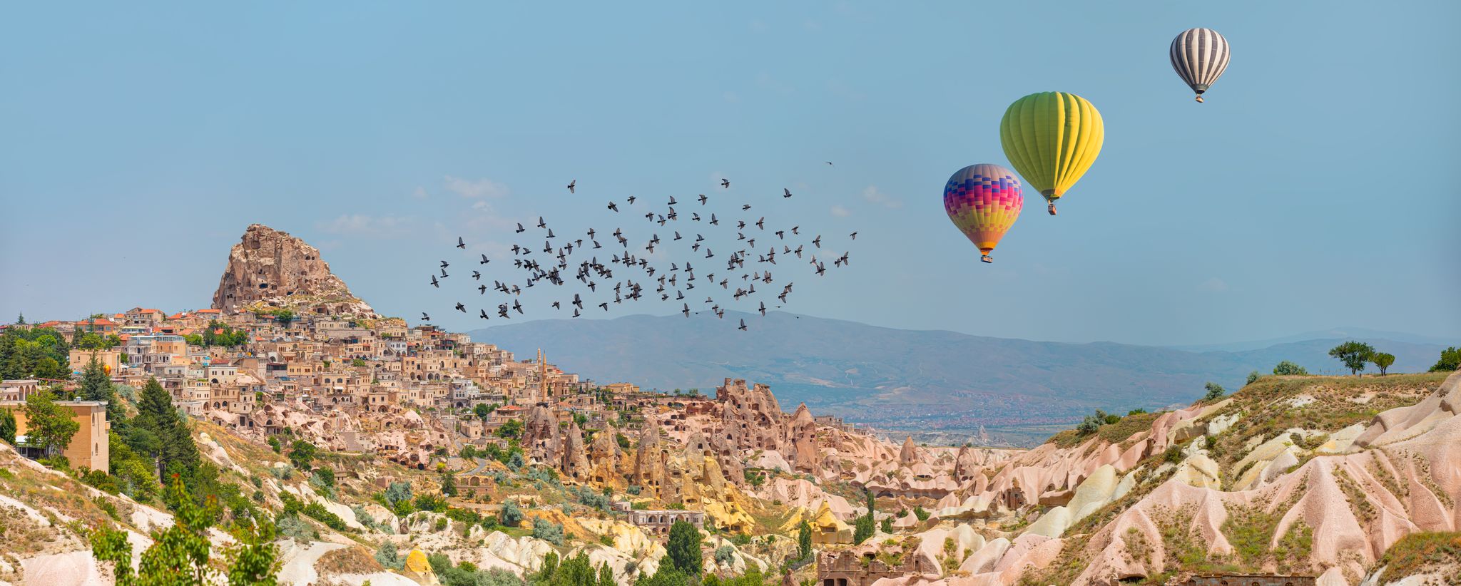 photo of hot air balloon flying over spectacular Uchisar castle and Pigeon valley in Cappadocia, Turkey.