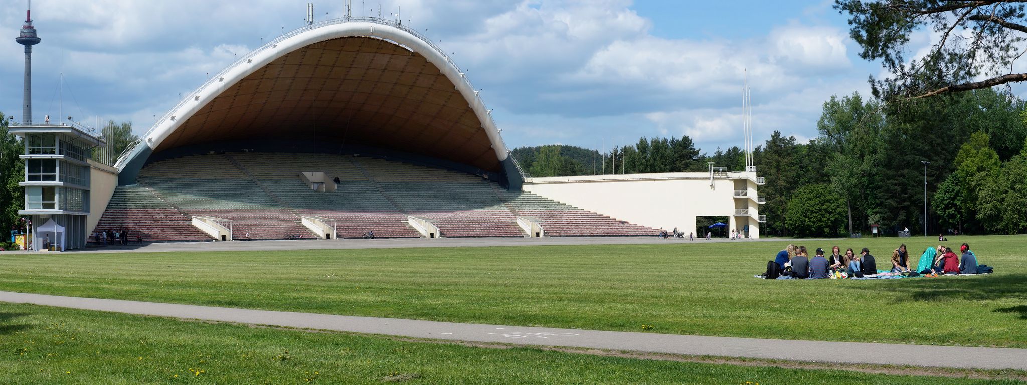 photo of Vilnius ,Lithuania - May 20, 2016: Tourists have rest on a spring lawn near the largest in Europe song theater scene in vingis park. The record of the viewers at a concert - 60 thousand in 1997.