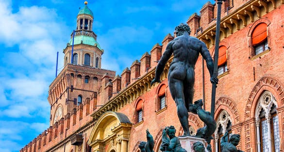 photo of The Fountain of Neptune (Fontana di Nettuno) with Palazzo d'Accursio in background in Bologna, Italy. Architecture and landmark of Bologna. Cityscape of Bologna.