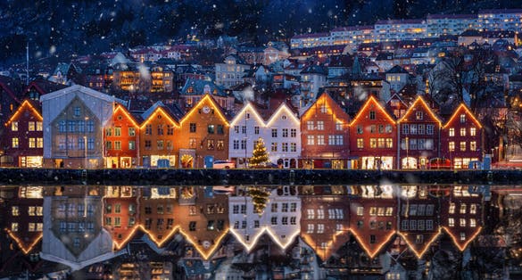 Winter dusk view of the famous Bryggen district at Bergen, Norway, decorated for Christmas with snow