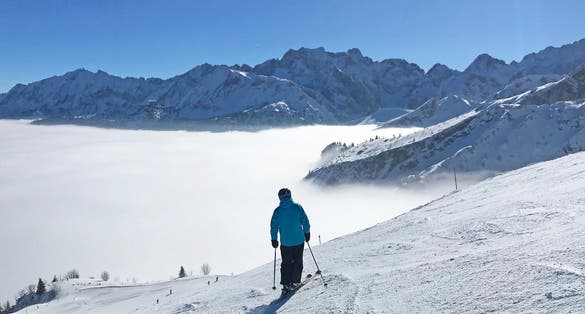 Photo of ski slope in Garmisch Partenkirchen over misty valley.