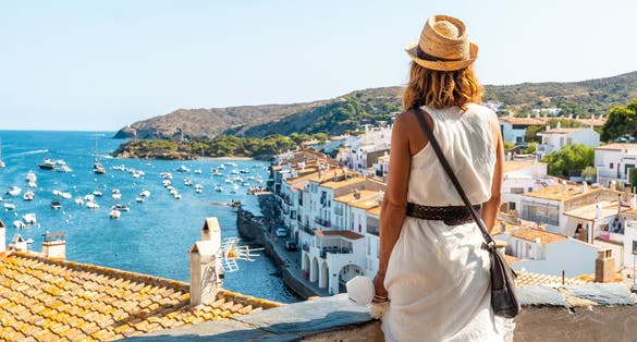 Photo of young woman on vacation looking at the city of Cadaques from a viewpoint, Costa Brava of Catalonia, Gerona.
