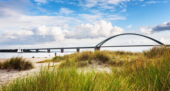 Photo of Fehmarn sound bridge. Late summer landscape with beach, dune grass and cloudy sky. Vacation background. Baltic sea coast, Germany, travel destination.