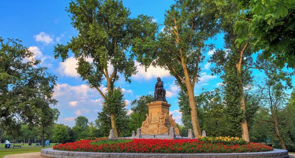 Photo of statue of Joost van den Vondel (1867) with tulips in the Vondelpark in Amsterdam, the Netherlands, on a beautiful spring morning.