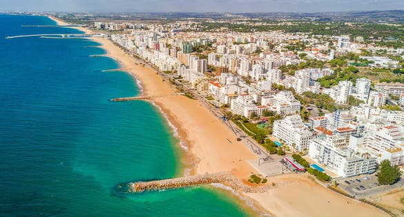 photo of an aerial view of wide sandy beach in touristic resorts of Quarteira and Vilamoura, Algarve, Portugal.