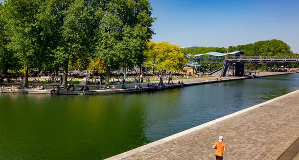 photo of a man running at La Villette while people are having picnic in Paris, France.