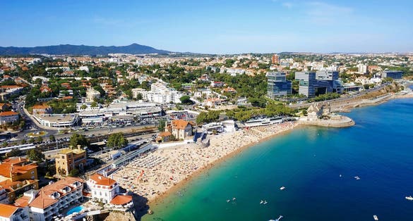 Photo of aerial view over People Crowd Having Fun On Beach And Over Cascais City In Portugal.