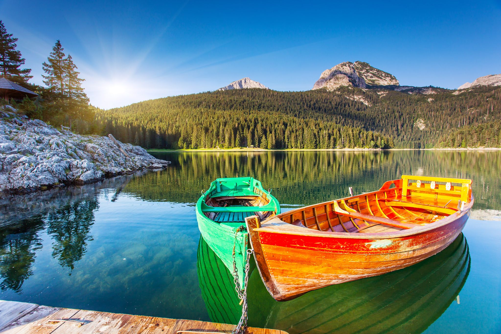 Photo of reflection in water of mountain lakes and boats. Black lake in Durmitor national park in Montenegro.