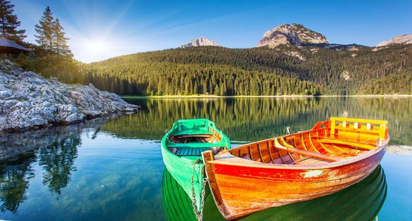 Photo of reflection in water of mountain lakes and boats. Black lake in Durmitor national park in Montenegro.