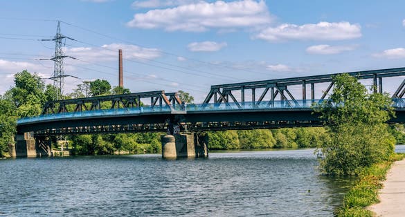 Photo of Ruhr River with old railroad bridge and modern footbridge in Bochum, Germany.