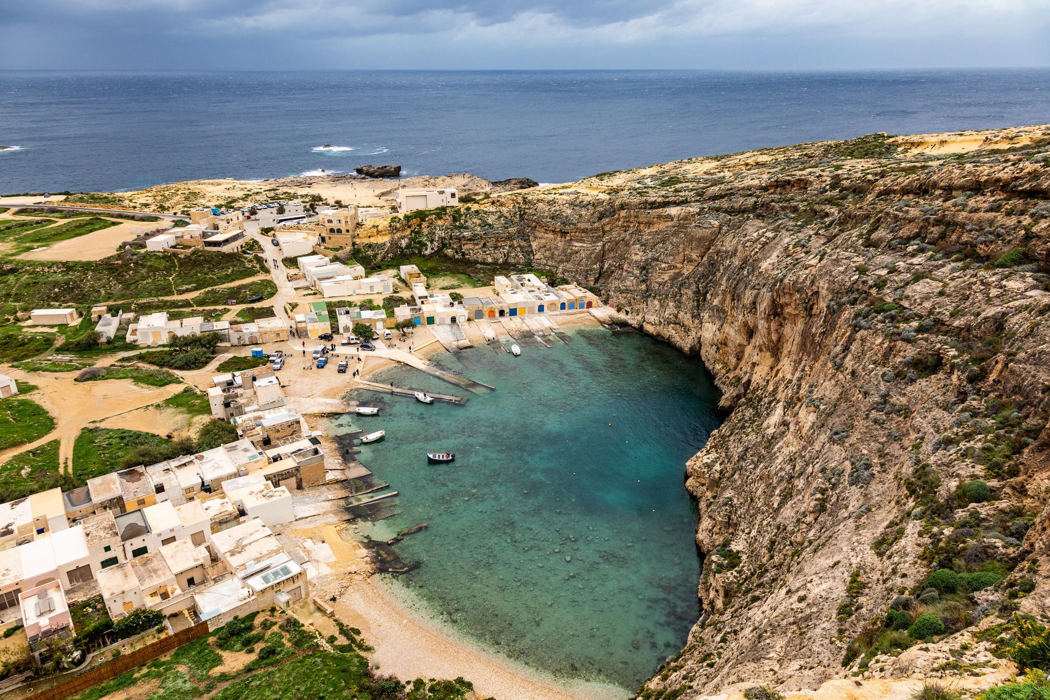 Photo of aerial view of seaside cliffs, colourful houses and streets of Qawra town in St. Paul's Bay area in the Northern Region, Malta.