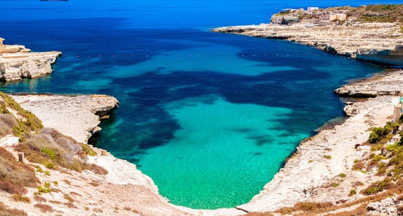 Photo of crystal clear turquoise water in blue lagoon of St. Peters pool  rocky beach at Malta.