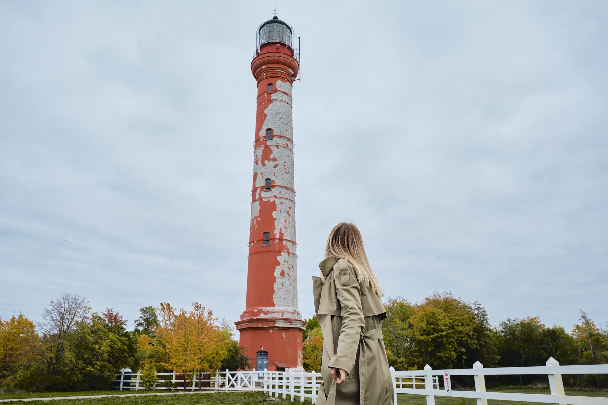 Photo of woman tourist looking at the red Pakri Lighthouse found in the town of Paldiski in Estonia one of the tourist spots in the city.