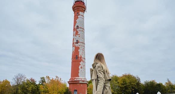 Photo of woman tourist looking at the red Pakri Lighthouse found in the town of Paldiski in Estonia one of the tourist spots in the city.