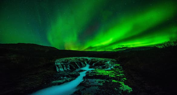 photo of Iceland Brúarfoss waterfall night view with northern light.