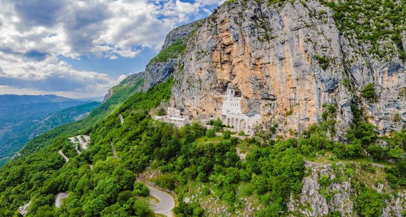 Photo of aerial view of Monastery of Ostrog is a monastery of Serbian Orthodox Church placed against an almost vertical rock of Ostroska Greda, Montenegro.