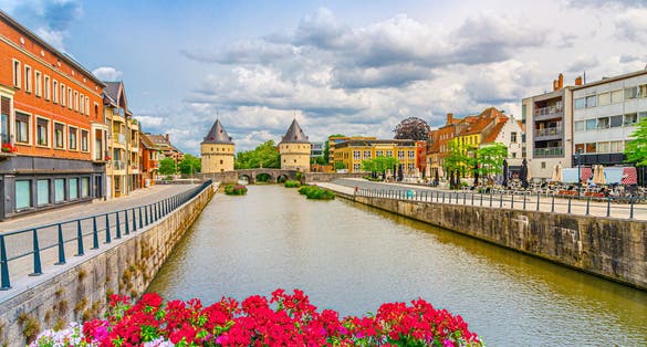 photo of view of Kortrijk cityscape, promenade of Lys river, Broel Towers buildings and Broel Bridge in Kortrijk city historical centre, red flowers, belgium landmark, West Flanders province, Flemish Region, Belgium
