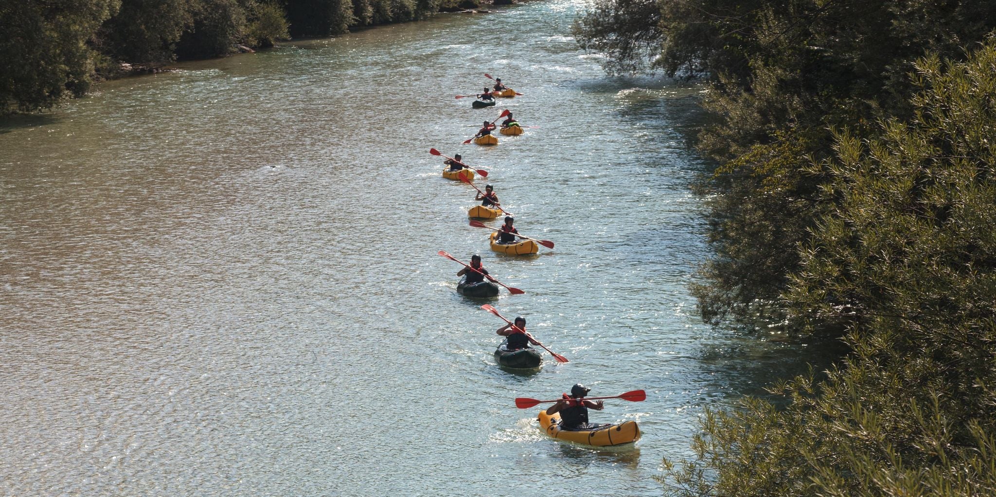 Group of people kayaking on the Soca River surrounded by forested banks in Slovenia..jpg