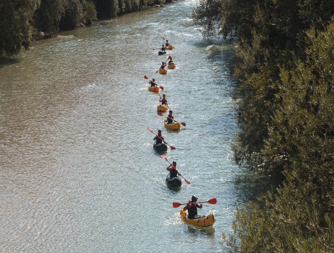 Group of people kayaking on the Soca River surrounded by forested banks in Slovenia..jpg