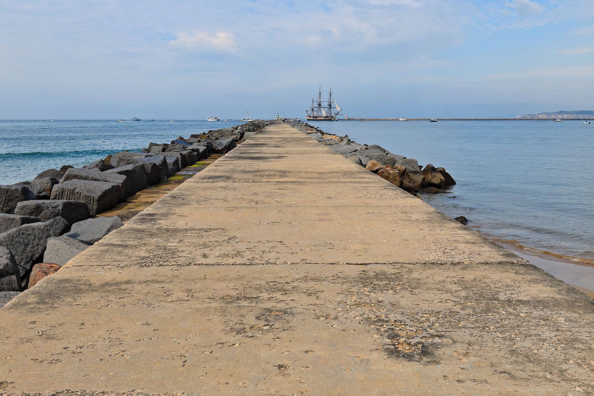 Portimao port's east outer mole at the mouth of the Arade river stretching into the ocean out from Praia do Molhe Beach-modern replica of a 1779AD French frigate to enter the harbor. Algarve-Portugal.