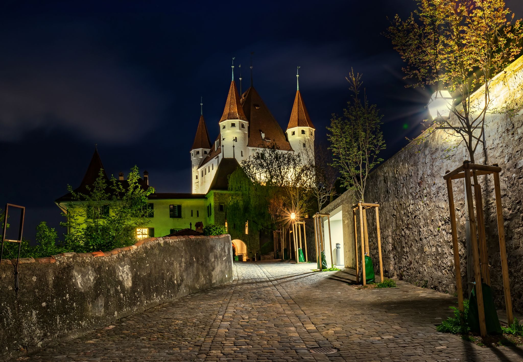 photo of nightscape of Thun, Bernese Oberland, Switzerland. Thun Castle illuminated at night under starry sky.