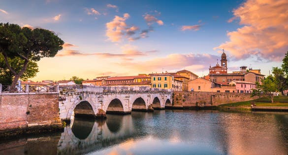 Photo of Rimini cityscape. Tiberius bridge famous sightseeing in Rimini at dawn. Summer sunrise in Rimini historic center.