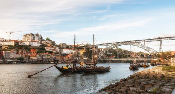 Ancient sailing vessels on Douro River. Dom Luis Bridge. Porto, Portugal.
