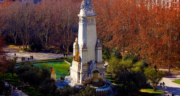 Photo of A view from above of people walking around the Miguel de Cervantes monument in the so called Spain Square. The photo shot is taken in the city center of Madrid, Europe. 