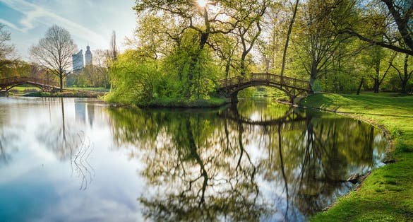 Photo of wooden bridge with a mirroring lake in Johanna Park Leipzig.