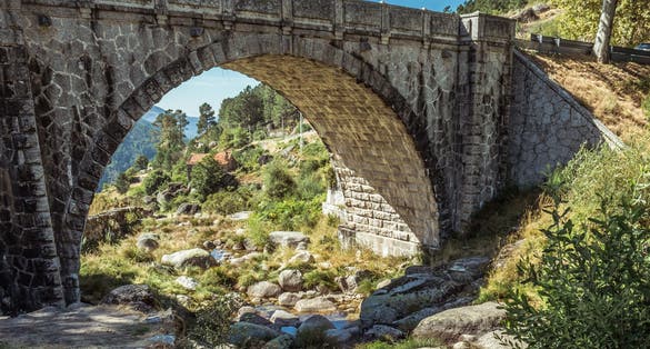 Small stream passing between stones under a Roman stone bridge overlooking the rural landscape in the Serra da Estrela Natural Park, Loriga, Seia ,PORTUGAL