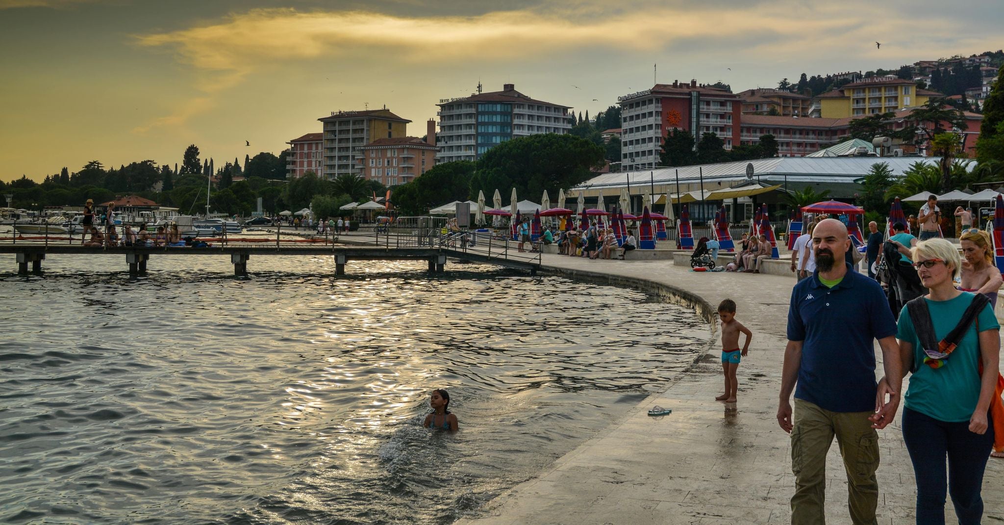 People walking and swimming along the waterfront promenade in Portoroz, Slovenia, at sunset..jpg