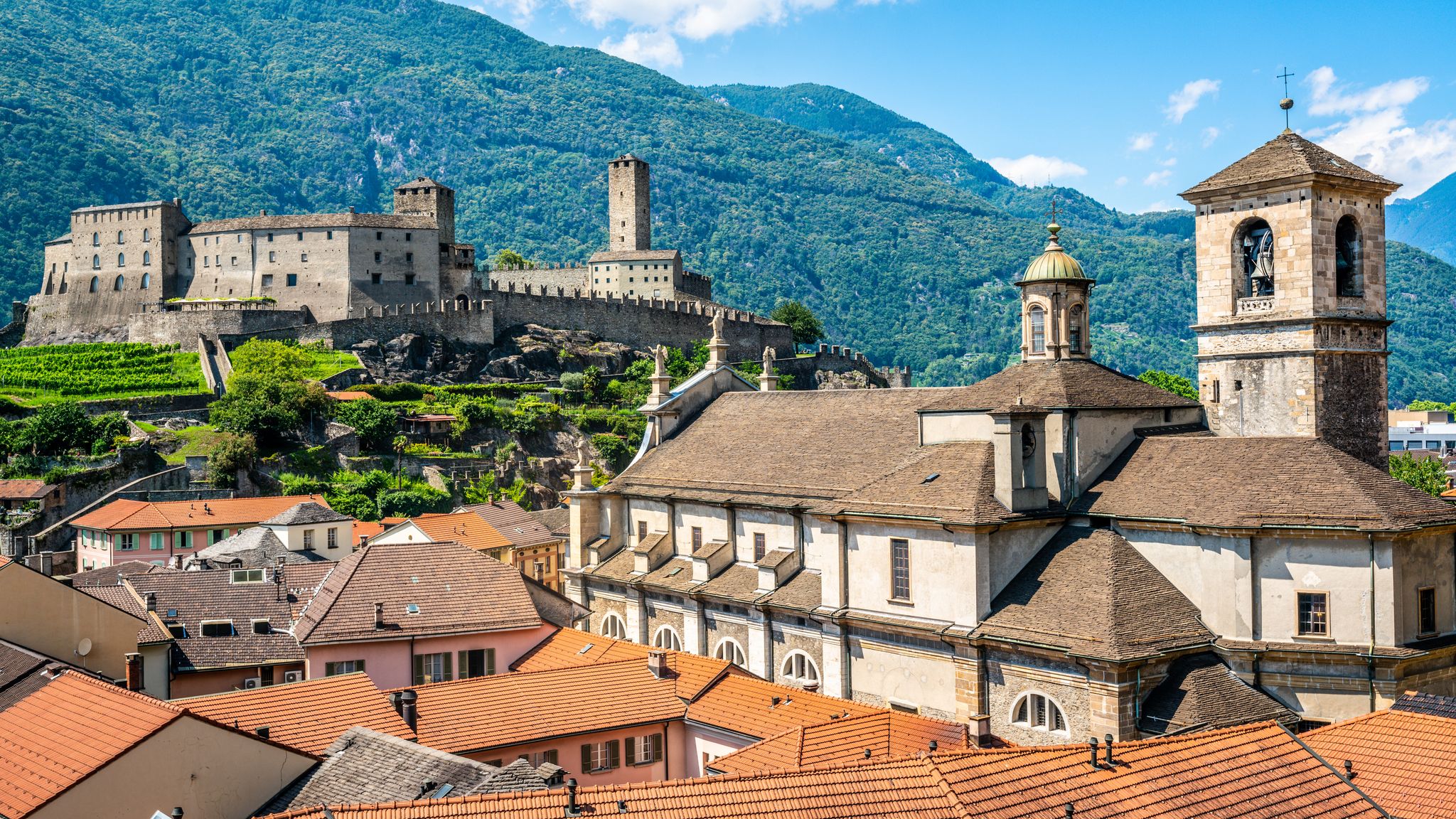 Photo of scenic cityscape of Bellinzona with Castelgrande castle and Chiesa Collegiata dei Santi Pietro e Stefano church in Ticino, Switzerland.