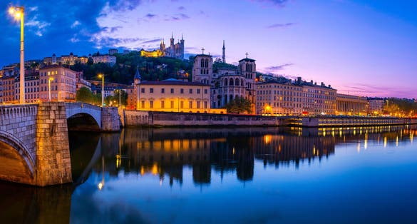 Lyon city skyline at night, over the Pont Bonaparte Bridge, vibrant water reflections on the Saone River, Saint George Church, and La Basilique Notre Dame de Fourvière in France