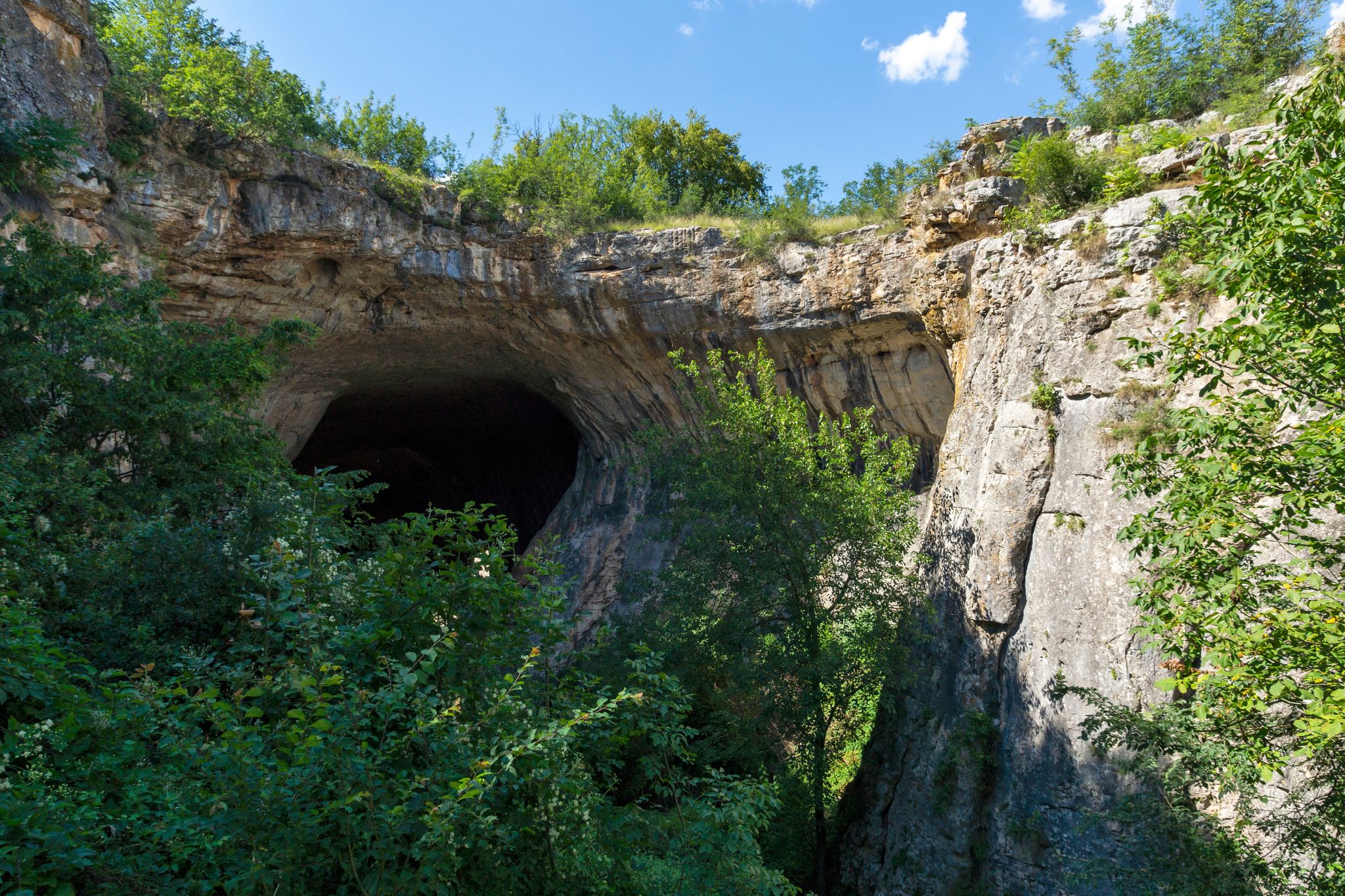 Photo of Prohodna cave also known as God's eyes near Karlukovo village, Bulgaria. Colorful cave with giant entrance.