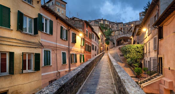 PHOTO OF Perugia, Italy. Medieval aqueduct and colorful buildings at dusk .