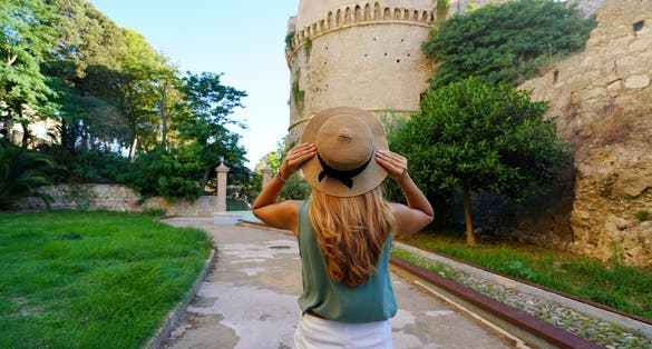 Photo of Tourism in Calabria. Back view of beautiful woman in Crotone with Charles V Aragon Castle in Crotone, Calabria, Italy.
