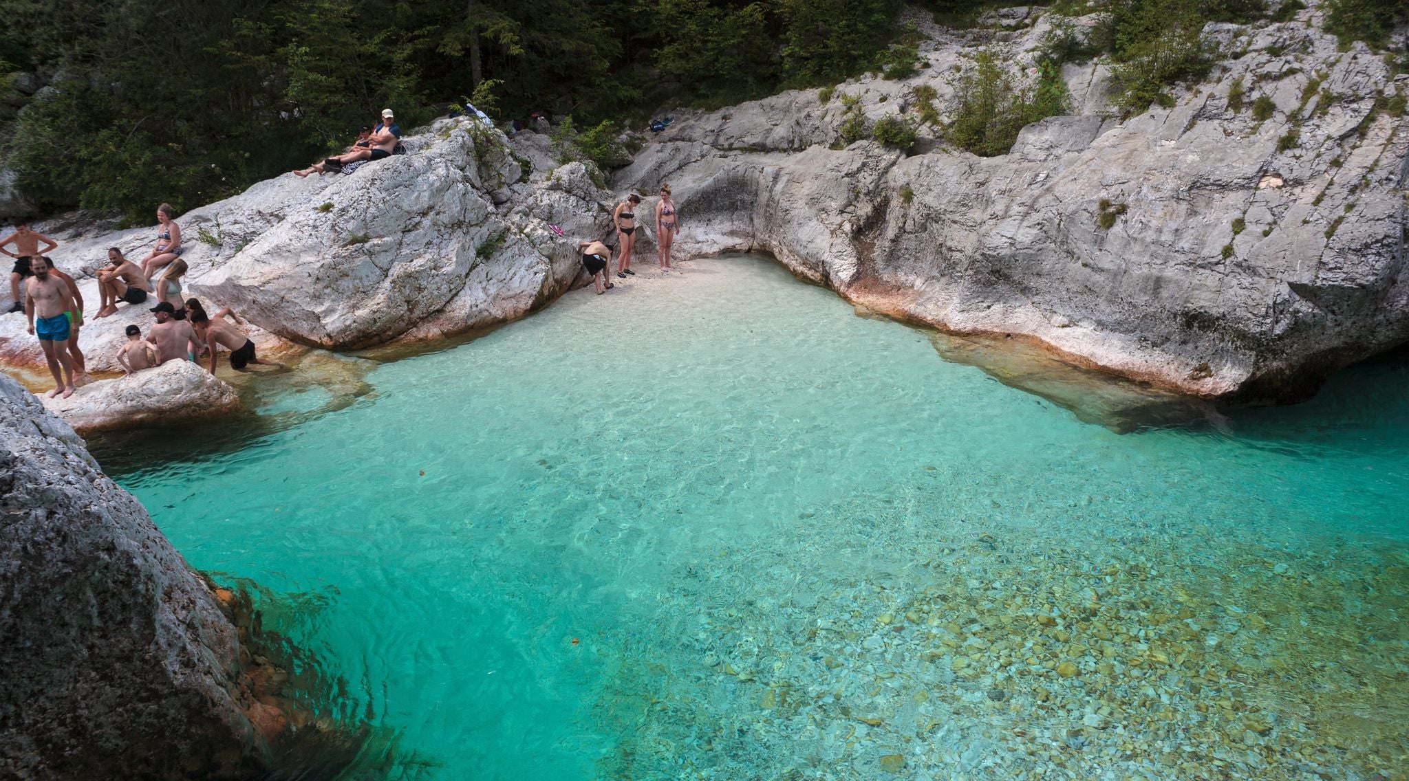 People relaxing by the turquoise waters of the Soca River at Great Soča Gorge in Slovenia..jpg
