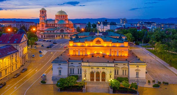 Photo of night view of the National Assembly of the Republic of Bulgaria and Alexander Nevski cathedral in Sofia.