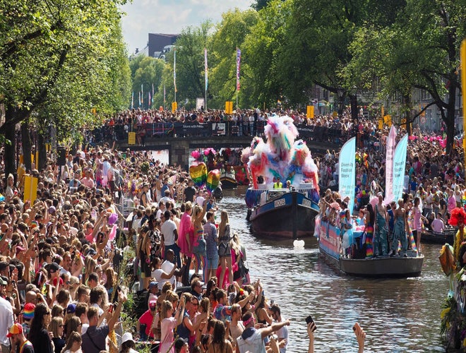 Colorful boats and cheering crowds at the Amsterdam Pride Canal Parade in August..jpg