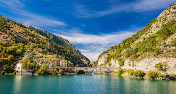 Lake San Domenico, in the Sagittario Gorges, in Abruzzo, L'Aquila, Italy. The small hermitage with the stone bridge. The turquoise color of the water. The glow of the sun, flare at sunset.
