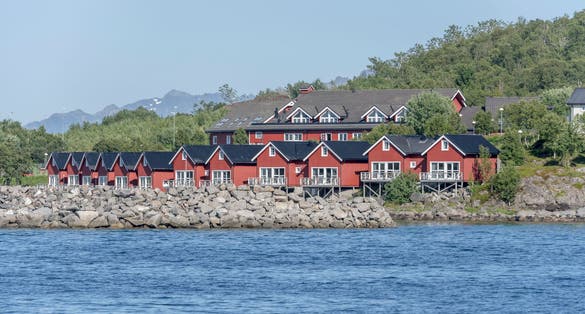 photo of view of picturesque traditional rorbuer on fjord shore, shot under bright summer light at Stokmarknes, Hadseloya, Vesteralen, Norway