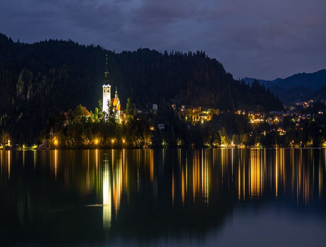 Lake Bled and the Church of the Assumption illuminated at night with reflections on the water..jpg