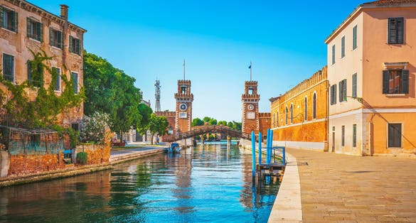 photo of view Venetian Arsenal with docks, canal and industrial building in a sunny day in Venice, Italy.