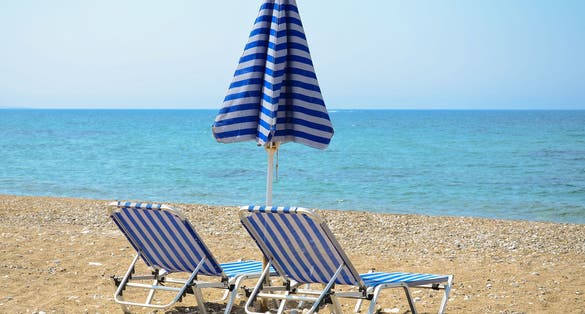 Photo of sandy beach with umbrella and sunbeds in Larnaca, Cyprus.